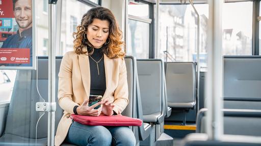 Businessfrau sitzt mit Handy in einem Bus